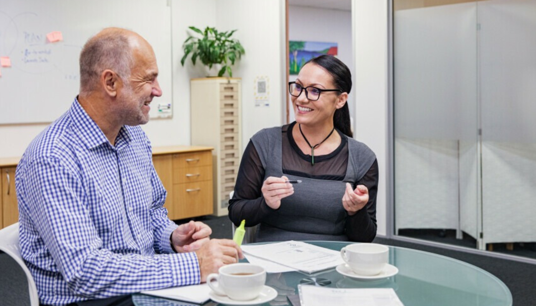 A couple are discussing something in an office, smiling
