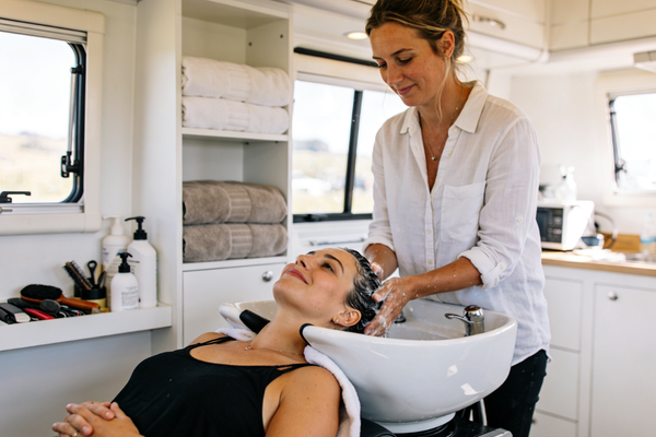 A hairdresser washes a woman's hair in a mobile salon