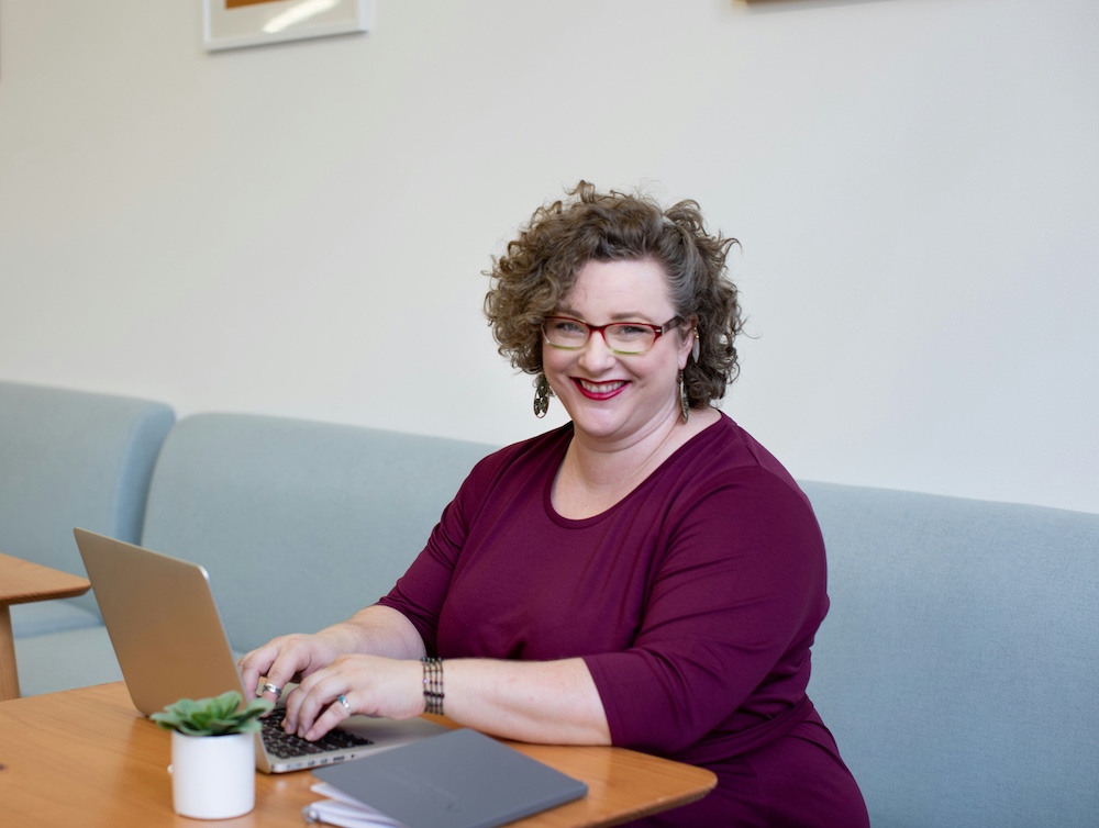 Plus size woman at work in bright, open office workplace with computer